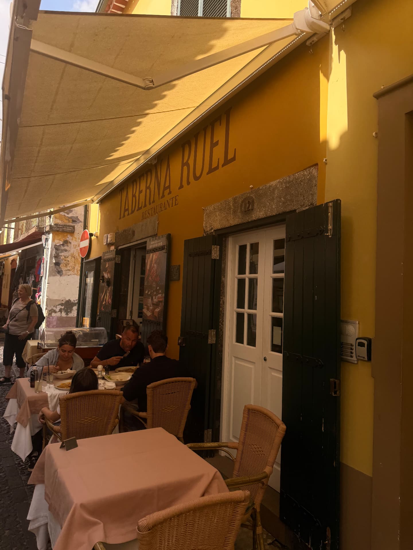 Fachada amarela do restaurante Taberna Ruel com portadas verdes