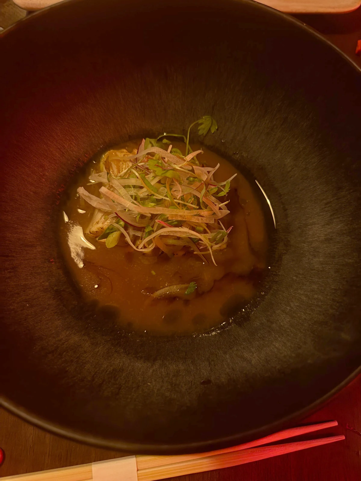 Dish topped with sliced onion and greens in a dark bowl at Yuki Funchal